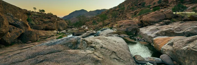 The Sonderseb River flowing through a narrow, ancient gorge; a rare occurrence after heavy rains that transforms the arid canyon into a living vein of water amidst the stone.