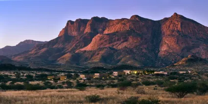 A wide-angle perspective of Hohenstein Lodge anchored at the foot of the monumental Erongo mountain range.