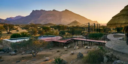 The emerald waters of the lodge pool contrasted against the ancient, sun-weathered granite of the Erongo peaks.