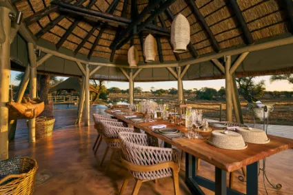 An architectural perspective of the open-air dining sala, documenting a refined culinary setting designed for communal connection amidst the wild.