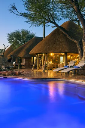 A wide-angle evening perspective of the villa's thatched structure reflecting in the pool, documenting the low-impact luxury of this exclusive sanctuary.