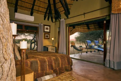 An intimate view of a luxury en-suite bedroom, where canvas walls and high-end textiles invite the textures of the bushveld inside.