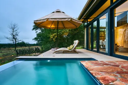 The private plunge pool of a guest villa, offering a secluded vantage point over the undulating red dunes and Camel-thorn trees.