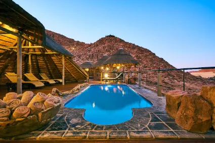 The central infinity pool, serving as a structural oasis with uninterrupted views across the gravel plains toward the Sossusvlei dunes.