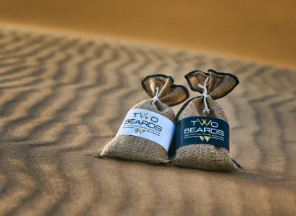 A study of Two Beards Coffee bags against the subtle, earthy tones of the Namib desert, symbolising the roastery's roots in the coastal wilderness.