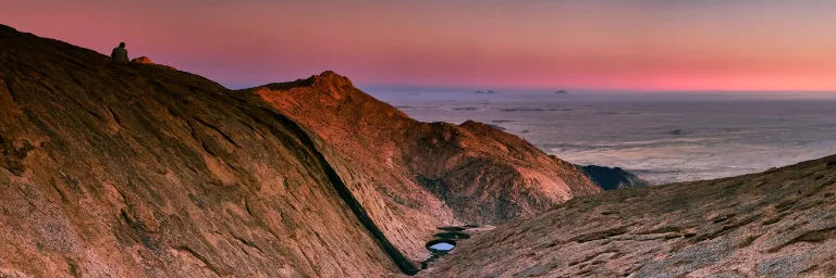 A lone figure sits atop a rugged granite peak overlooking a vast, ancient landscape—a moment of silent contemplation amidst the mysteries of the high-altitude sanctuary.