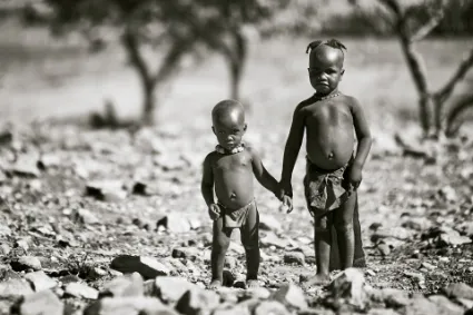 Two young Himba boys setting out to tend the family cattle, illustrating the early responsibilities and purpose-filled life of the northern nomadic youth.