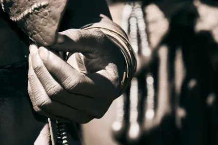 A detailed study of a Himba woman's hand adorned with traditional copper and leather bracelets, showcasing the intricate craft of their customary attire.