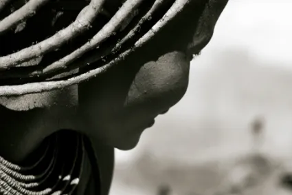 An abstract portrait of a Himba individual, focusing on the interplay of light, shadow, and the rich textures of traditional ochre-tinted skin.