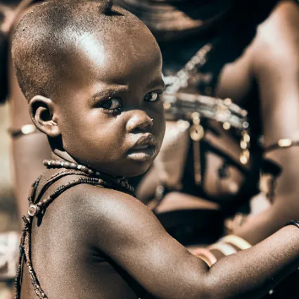 A portrait study of a young Himba child, capturing the vibrant spirit and resilience of a life lived in harmony with the wild.