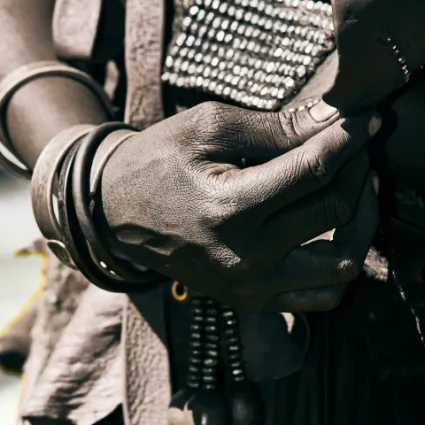 A close-up study of a Himba woman's hand, emphasising the tactile connection between the people and the natural materials of their environment.