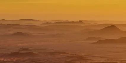 A monumental vista from the high peaks of the Brandberg, looking out over the vast coastal plains of the Namib; a perspective of the 'Realms of the Gods' where the mountain meets the sky.