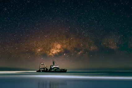The Zeila shipwreck on the Skeleton Coast under a crystalline early morning sky, with the Milky Way visible above the Atlantic surf.