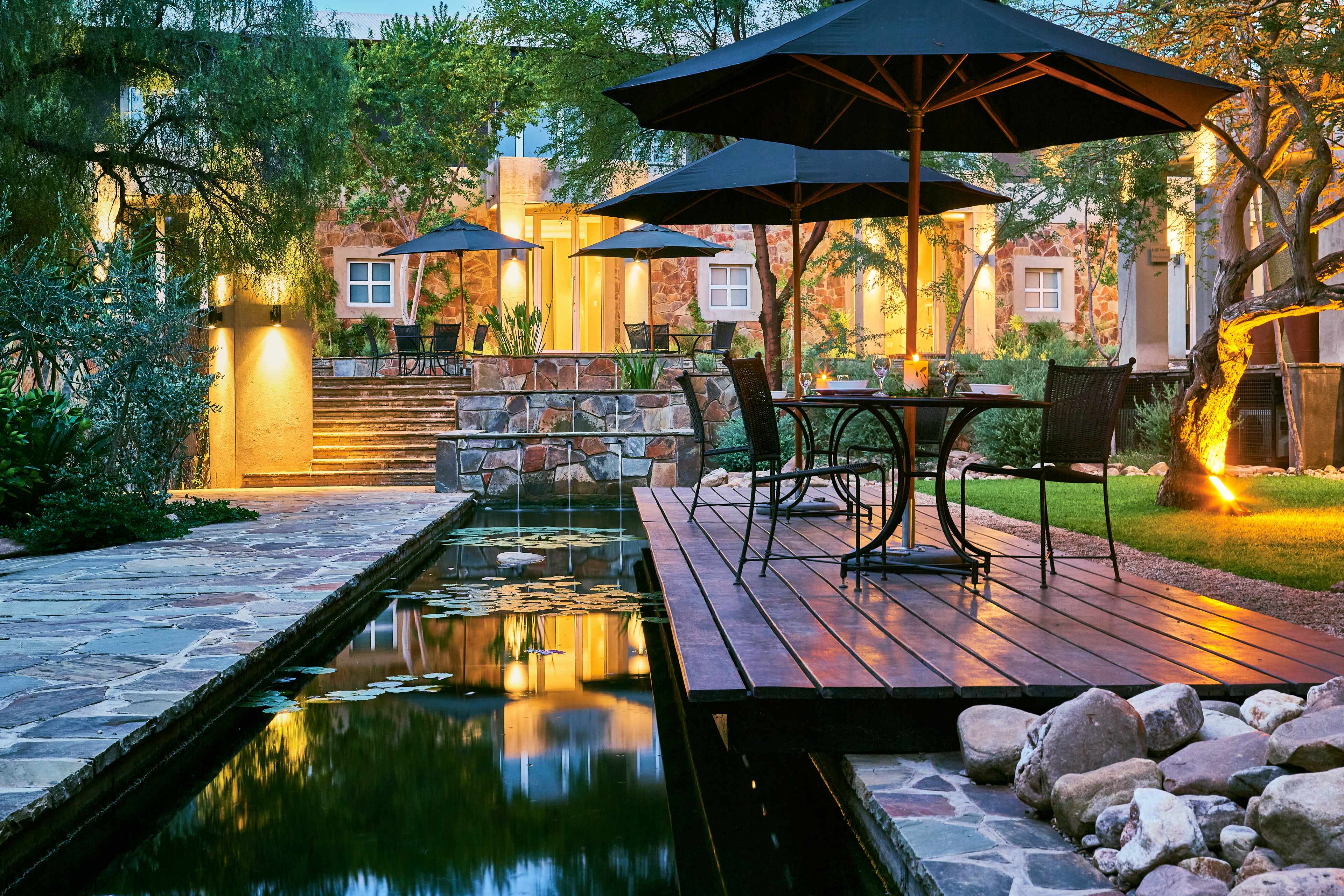 Peaceful evening at Fresh and Wild in Windhoek, featuring a reflective pond, ambient lighting, and a welcoming outdoor deck for a relaxing experience.