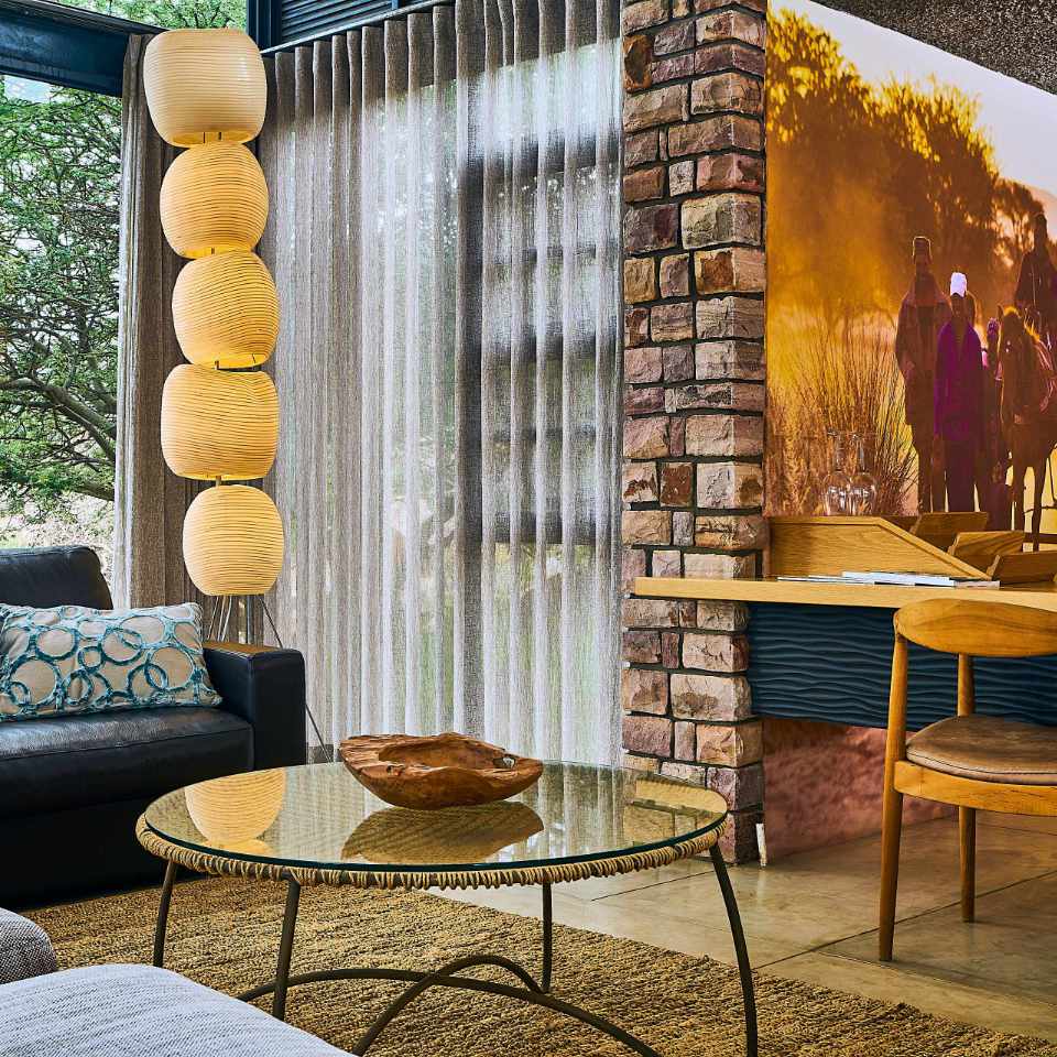 Elegant and modern interior of Otzimbondona Lodge featuring eclectic decor, vibrant yellow lanterns, and a cozy dining area with a view of the Namibian landscape.