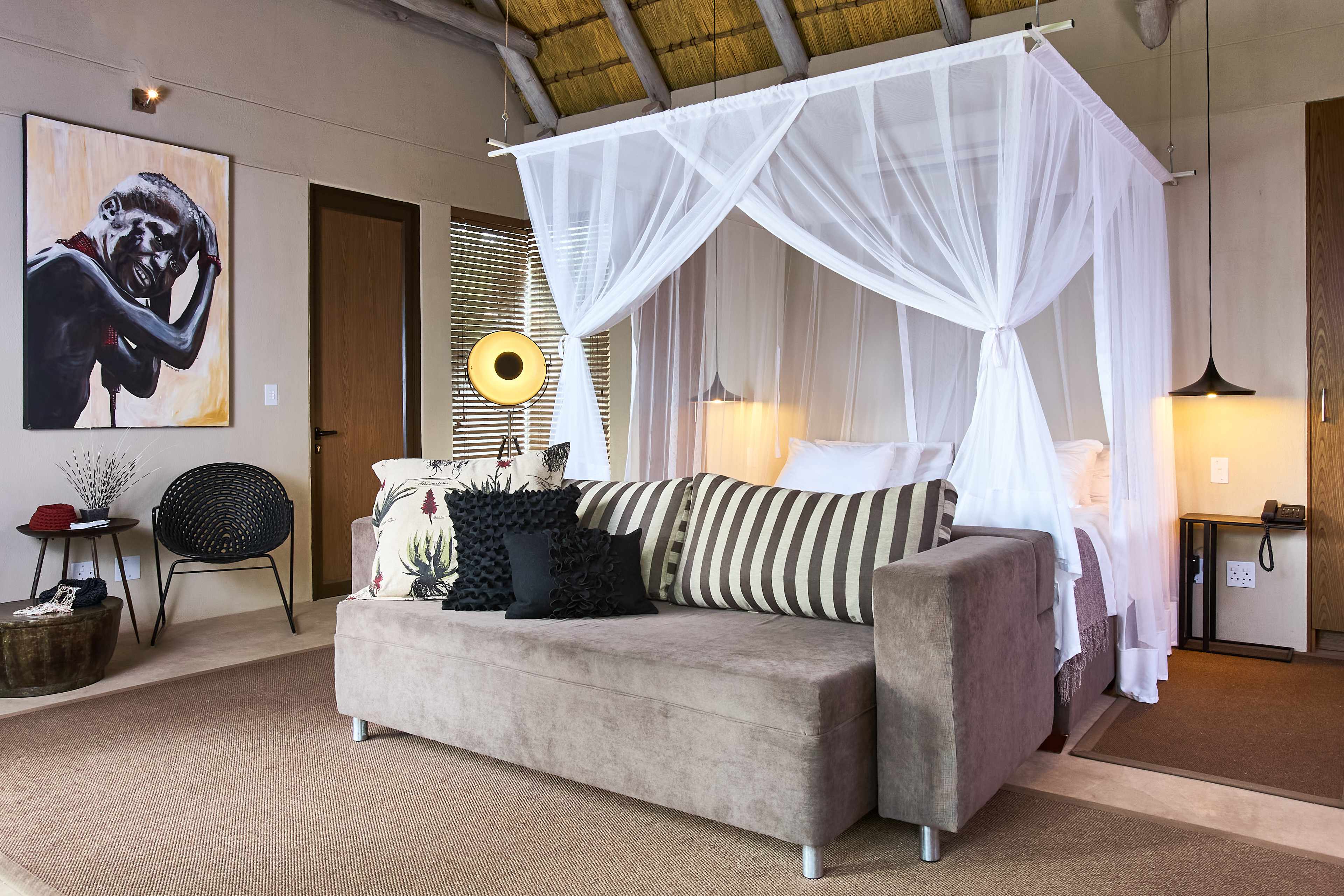 Spacious and elegantly furnished chalet at Popa Falls Resort, Duwundu, Caprivi, featuring a luxurious bed, contemporary decor, and artistic touches.