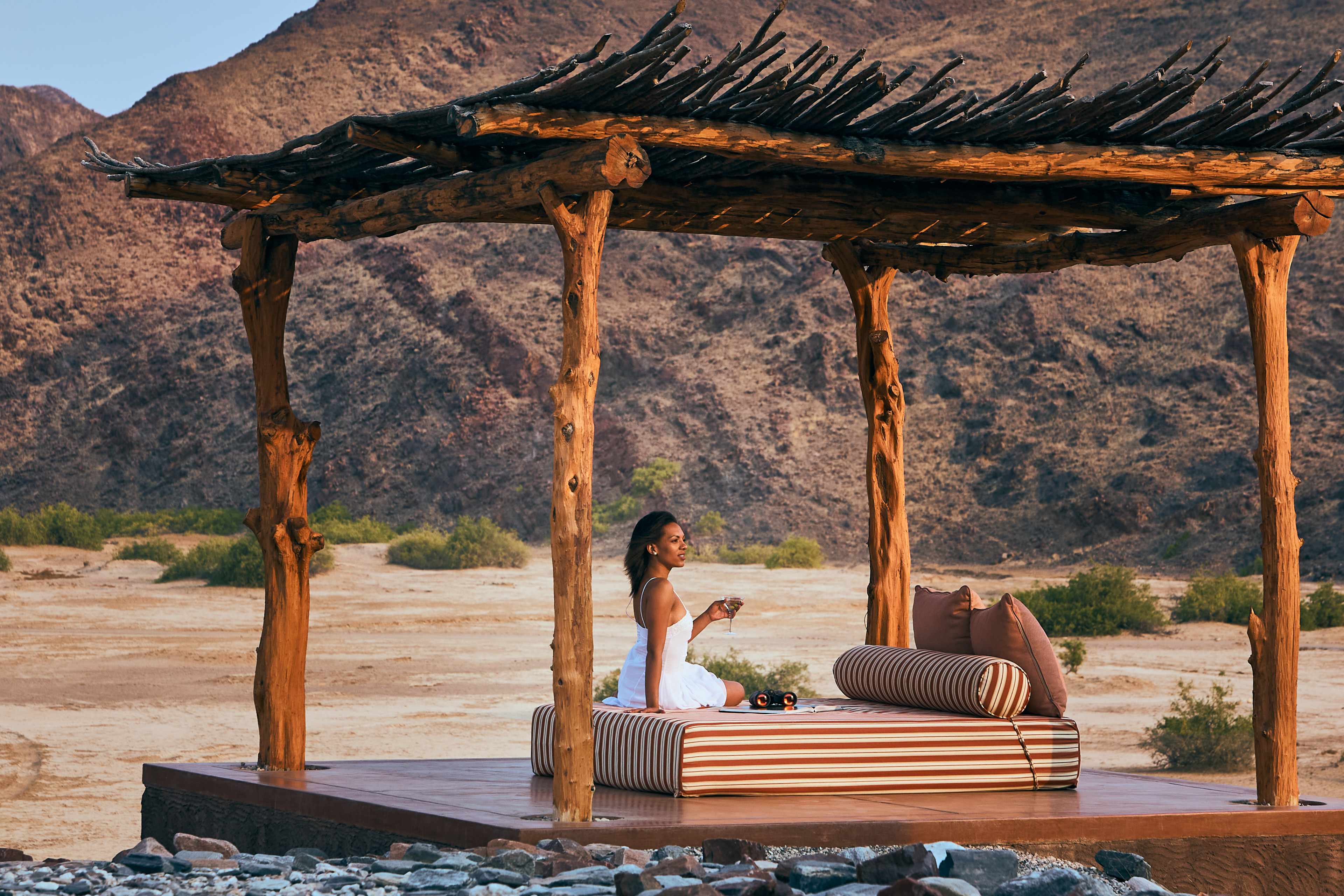 Tranquil relaxation area at Okahirongo Lodge in Purros, Northern Namibia, featuring a thatched-roof structure and panoramic desert views.