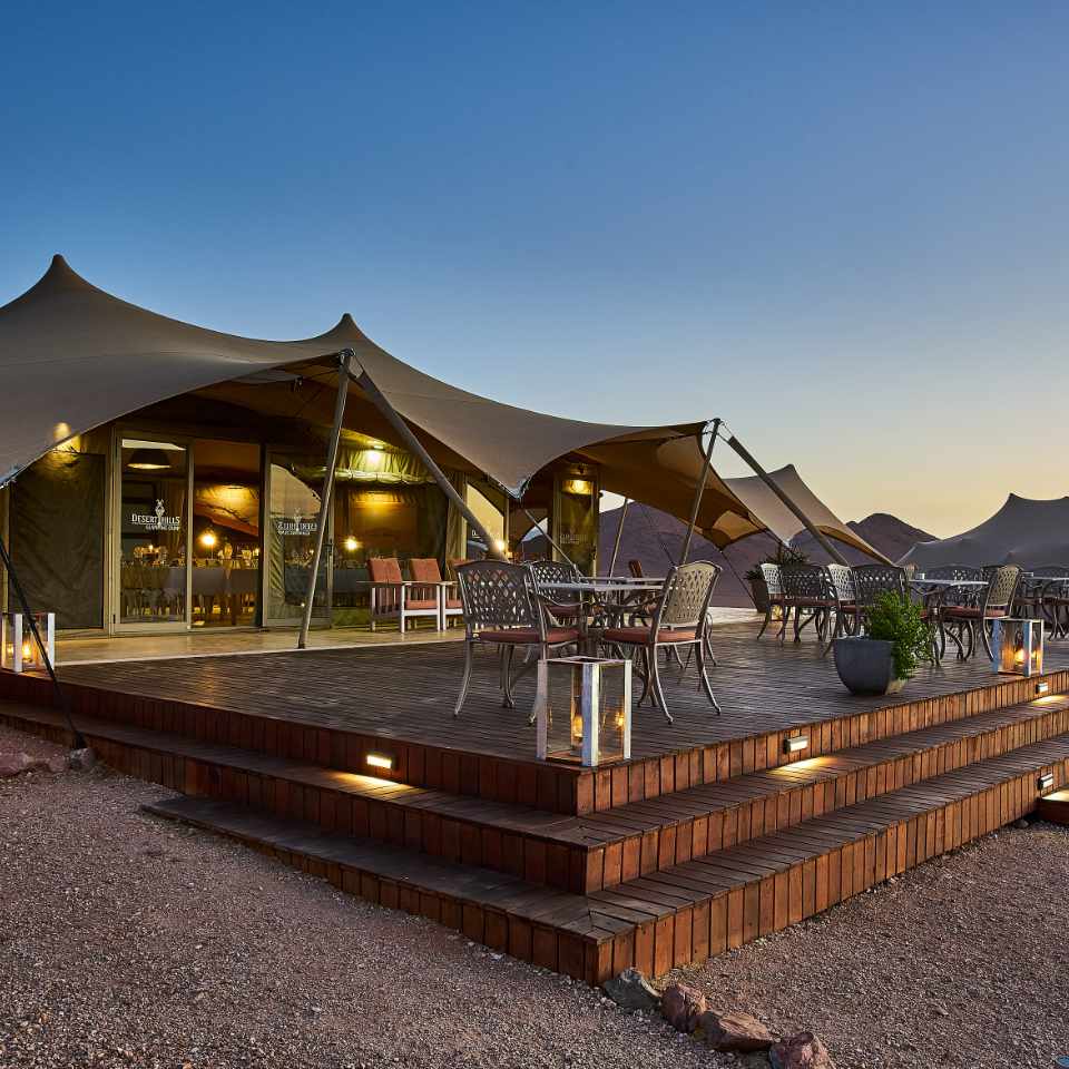 Luxurious twilight glamping at Namib Hills, with elegant tents and wooden decks against the backdrop of mountains east of Sossusvlei.