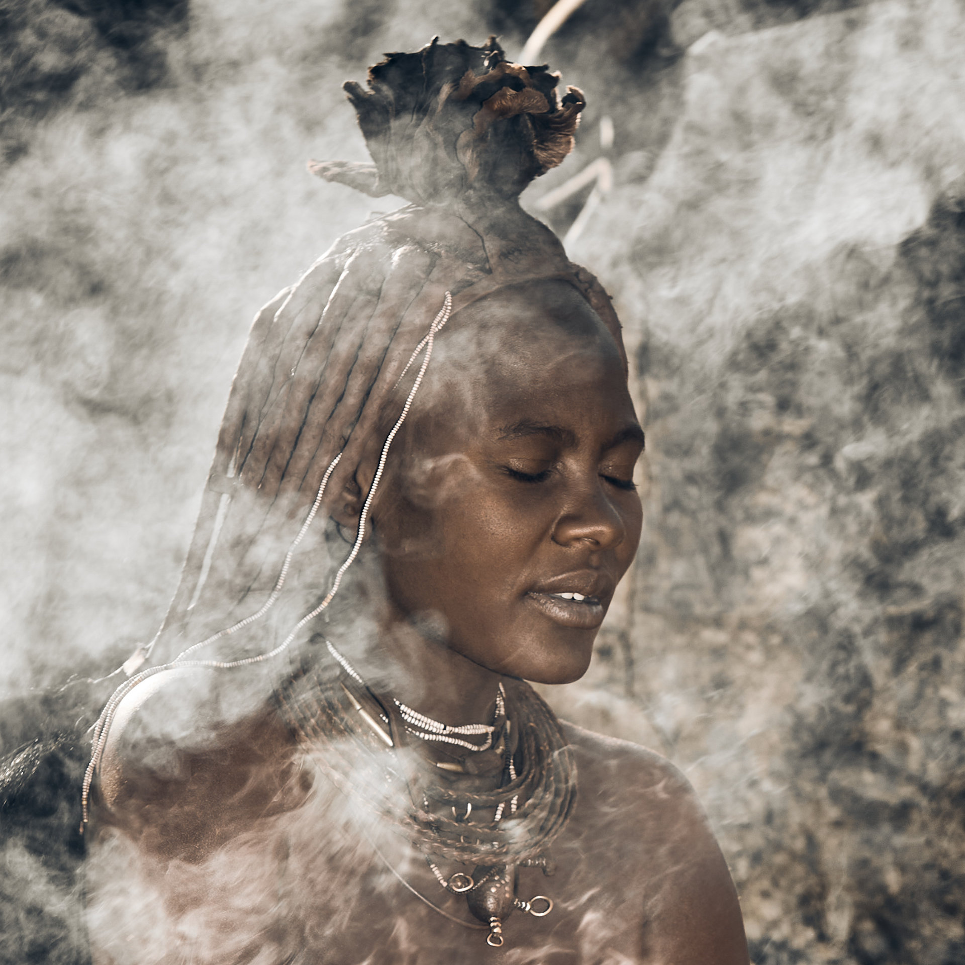 Himba Culinary Tradition: A Himba woman from northern Namibia enveloped in the aromatic smoke of a traditional cooking fire, showcasing the rich cultural heritage.