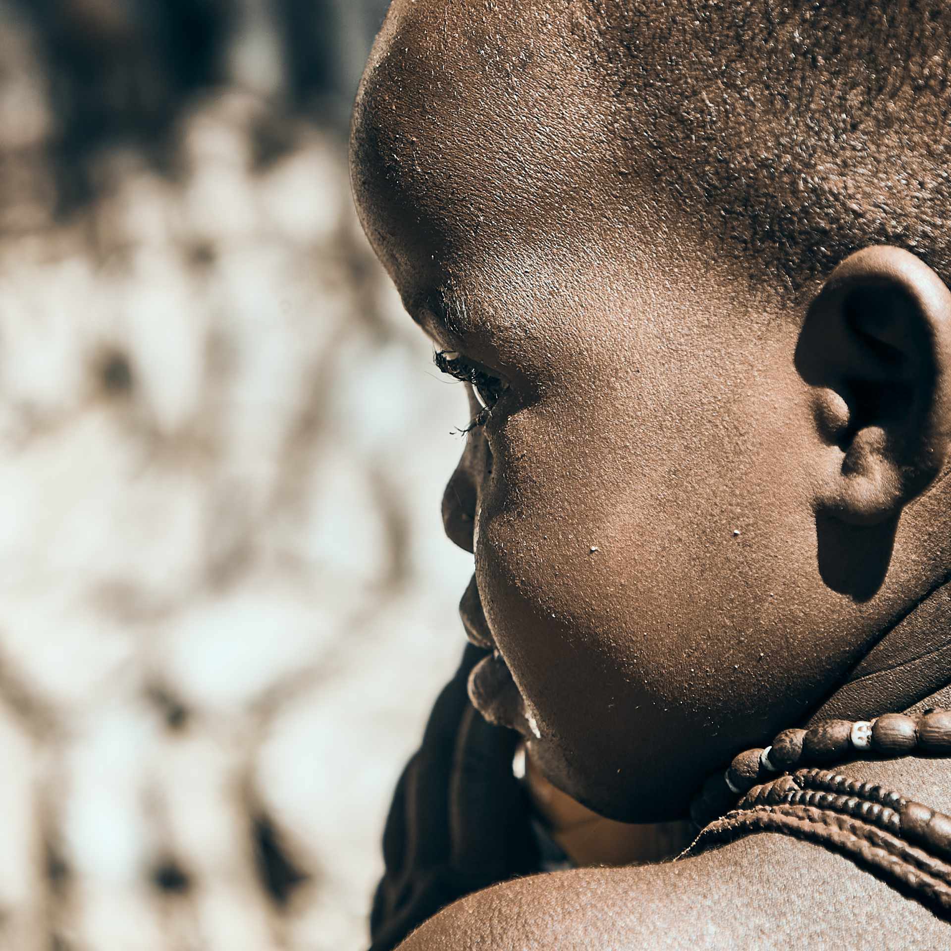 Portrait of a young Himba child adorned with traditional jewelry, showcasing the cultural heritage of northern Namibia.