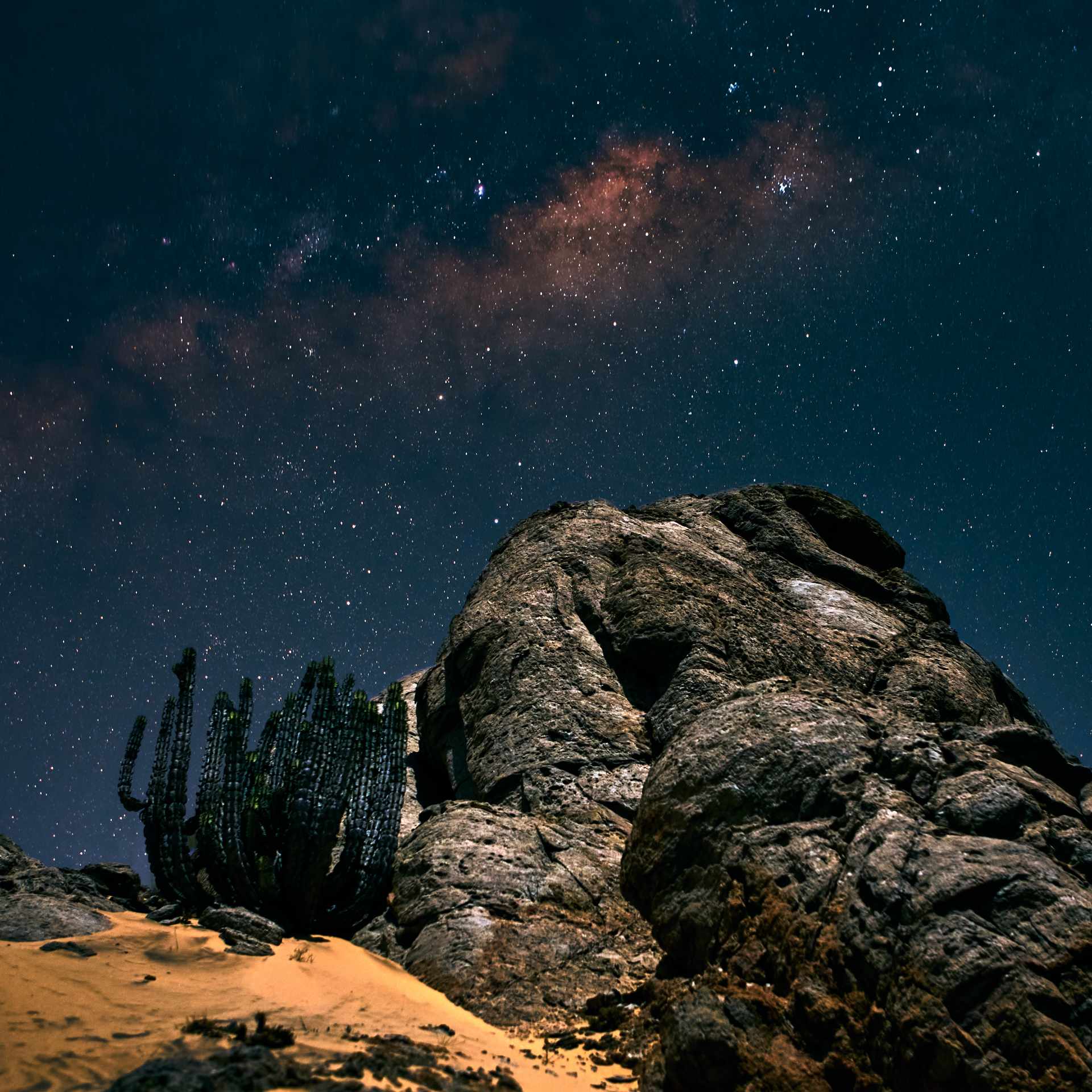 Starry night over the Skeleton Coast, with a clear view of the Milky Way illuminating the rocky landscape and sand dunes, no mist in sight.