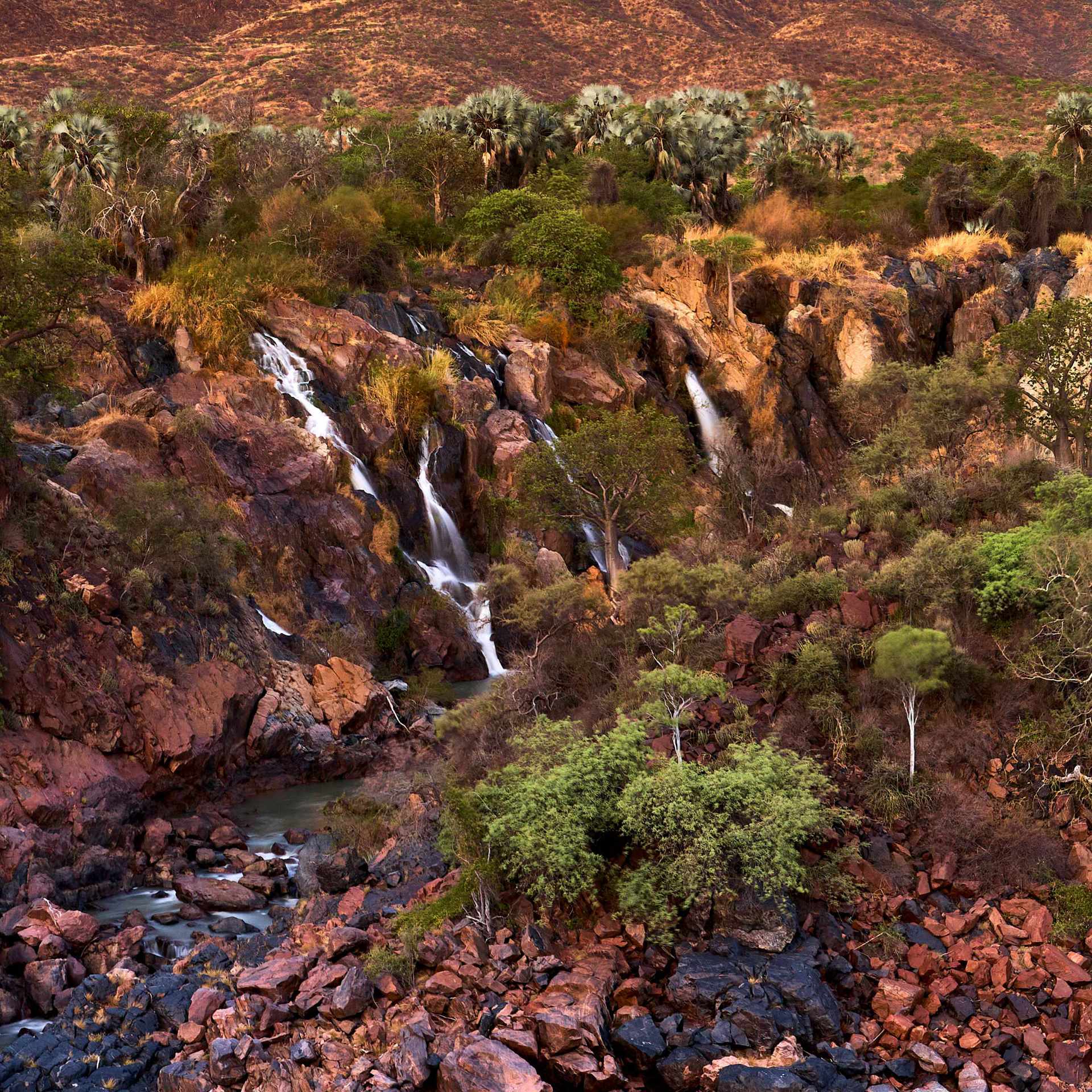 Photograph of Epupa Falls at a lower water level, framed by the iconic baobab trees of the region.